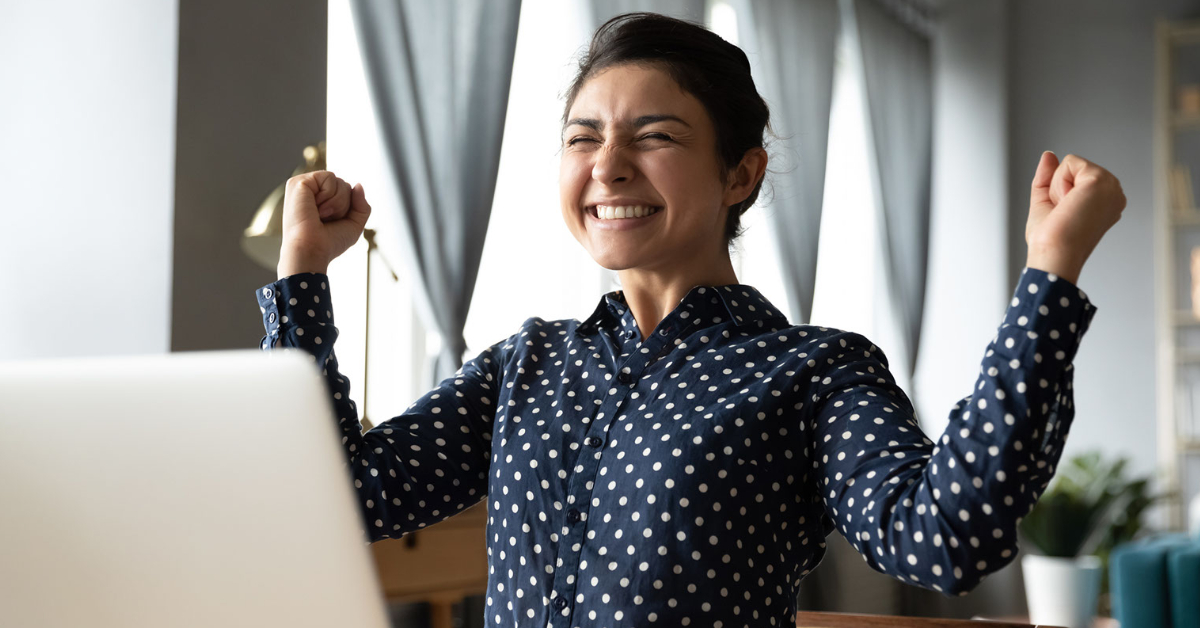 Woman happy in front of laptop at her desk after she got a good job offer